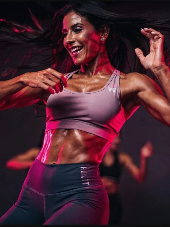 Mulher dançando em aula de fit dance, iluminação magenta