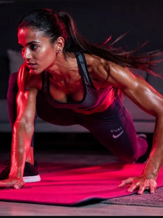 Mulher em treino funcional em casa, iluminação rosa cinematográfica